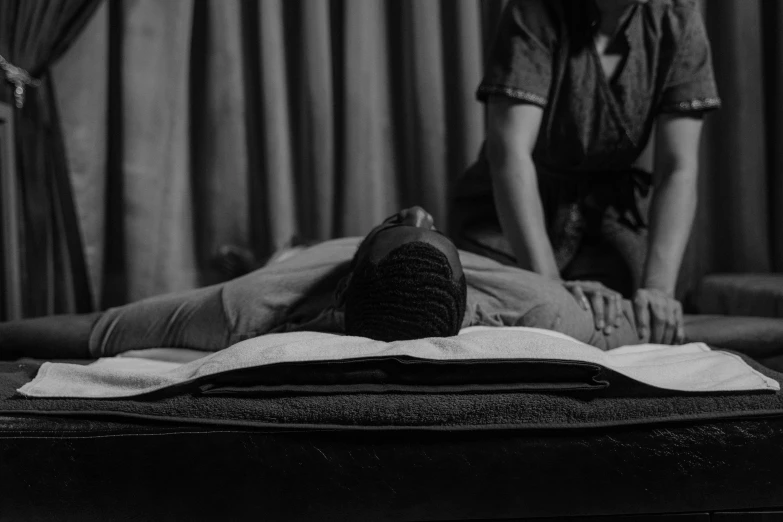 a black and white photo of a woman getting a back massage, unsplash, massurrealism, man is with black skin, laying back on the bed, gif, buddhist