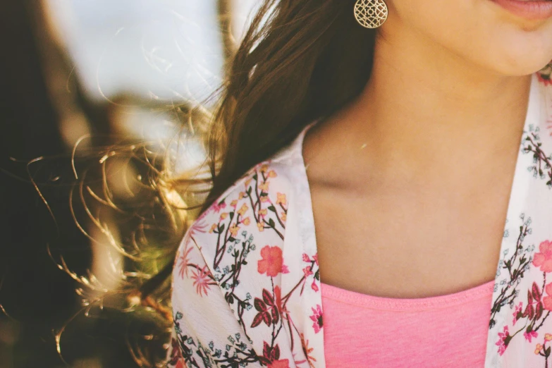 a close up of a woman wearing a pink shirt, a picture, trending on pexels, arabesque, wearing a cardigan, floral bling, spring fashion, pretty clothing!