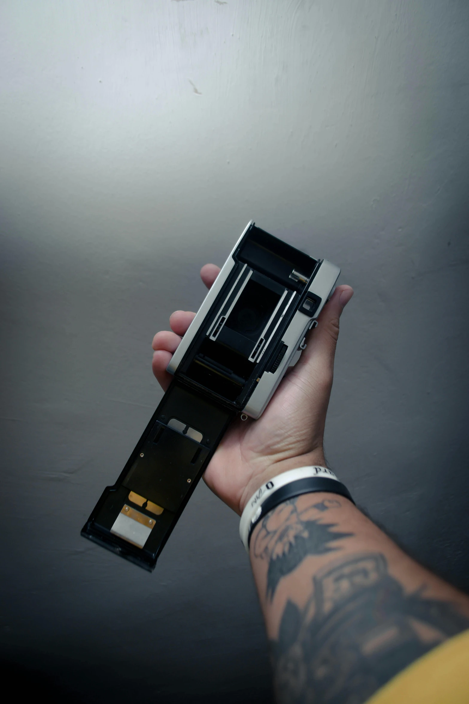 a person holding a cell phone in their hand, a polaroid photo, by Glennray Tutor, unsplash, a folding knife, bottom view ， bladerunner, medium format, black 3 d cuboid device