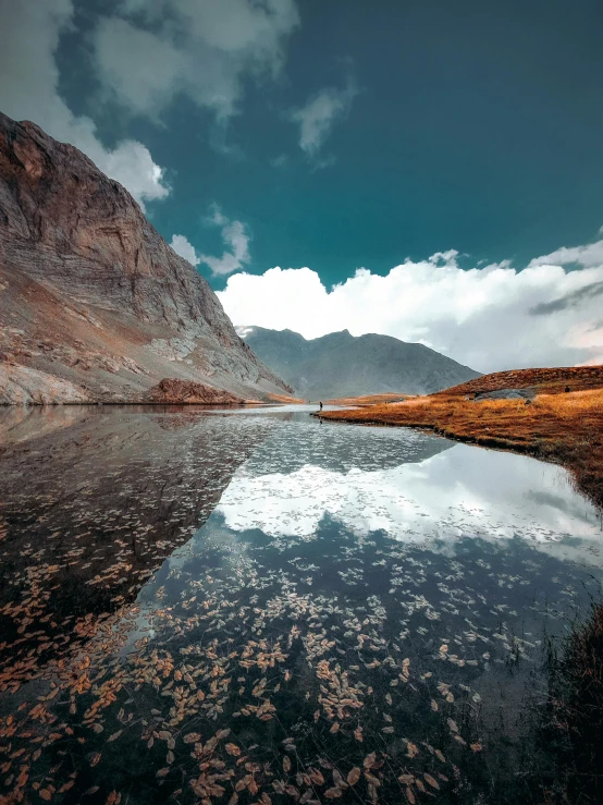 a lake near some mountains and grass in the middle of nowhere