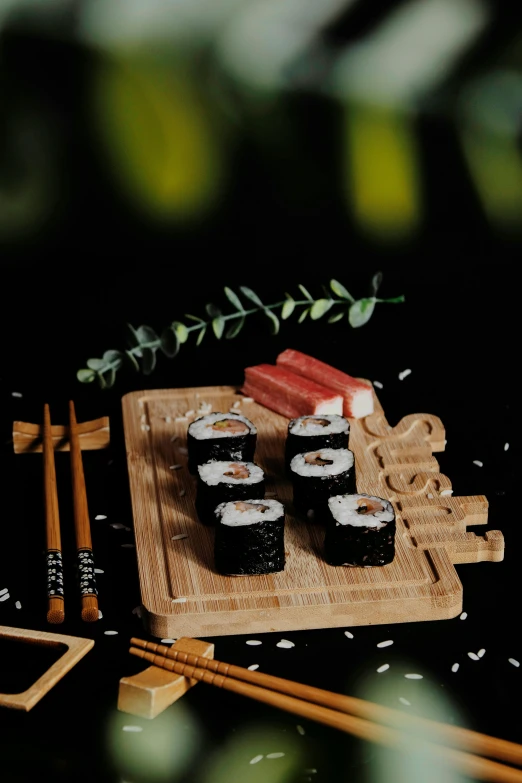 a wooden cutting board topped with sushi and chopsticks, by Julia Pishtar, purism, kanji, oasis infront, malaysian, black
