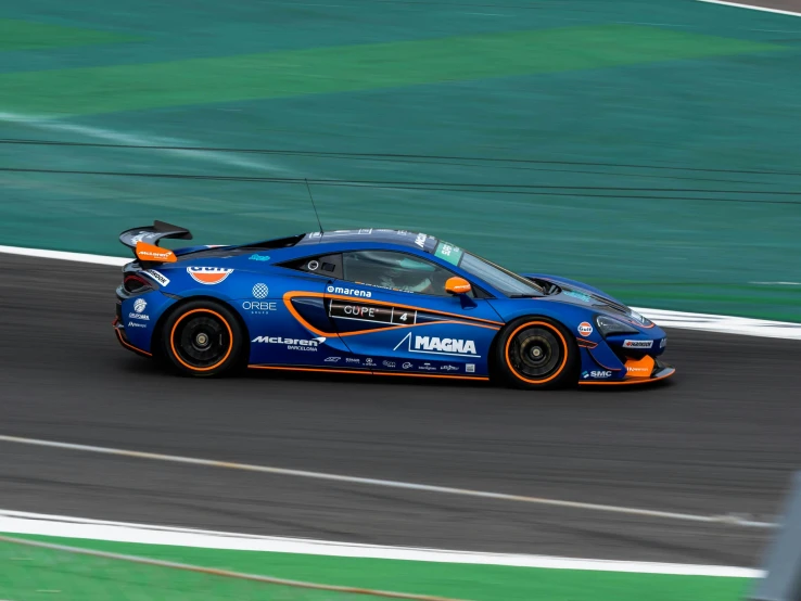 the blue and orange racing car drives on the track