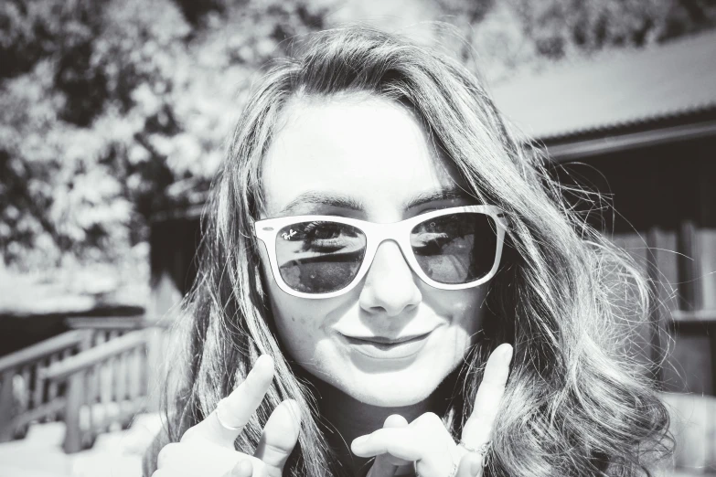 a black and white photo of a woman wearing sunglasses, unsplash, photorealism, portrait of white teenage girl, giving the middle finger, sunny day time, pokimane