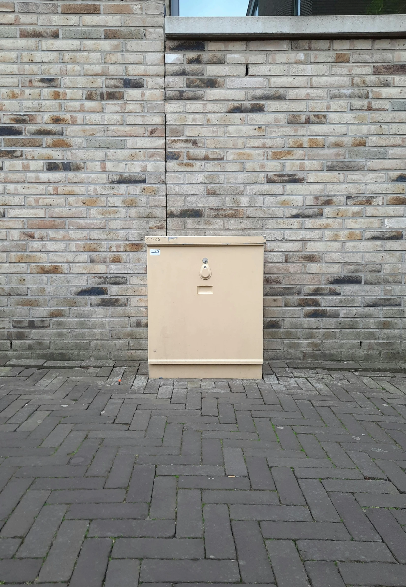 a closed storage cabinet on a sidewalk near a building