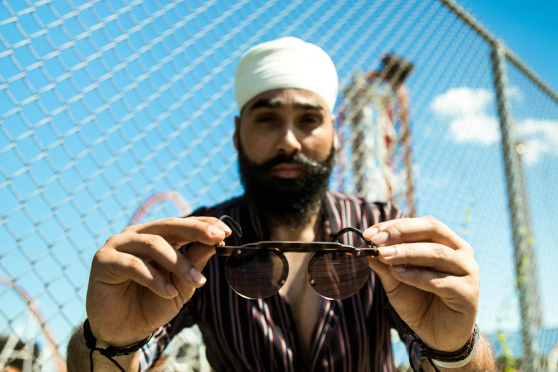 a man is holding up sunglasses and standing in front of a net