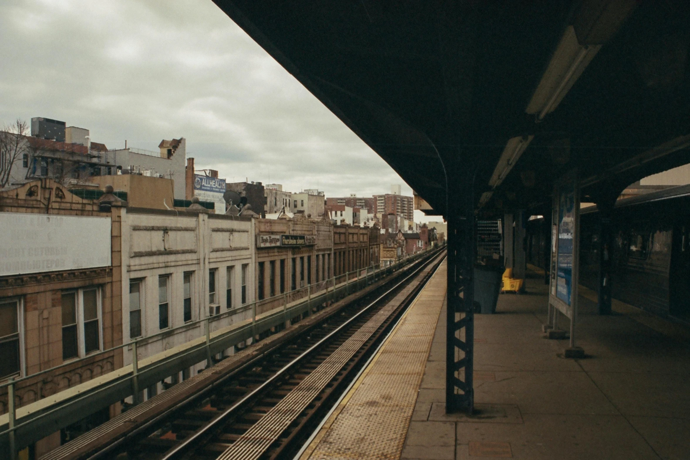 a train traveling down train tracks next to a tall building, a photo, unsplash contest winner, harlem renaissance, subway station, ignant, 2000s photo, porches