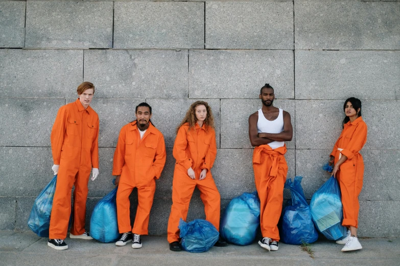 a group of people standing next to each other, by Julia Pishtar, pexels contest winner, arte povera, wearing orange prison jumpsuit, mad trash bags, blue planet still, julian ope