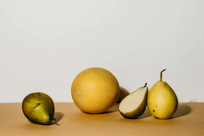 a group of pears sitting on top of a table, product image, neutral light, gradient light yellow, ignant