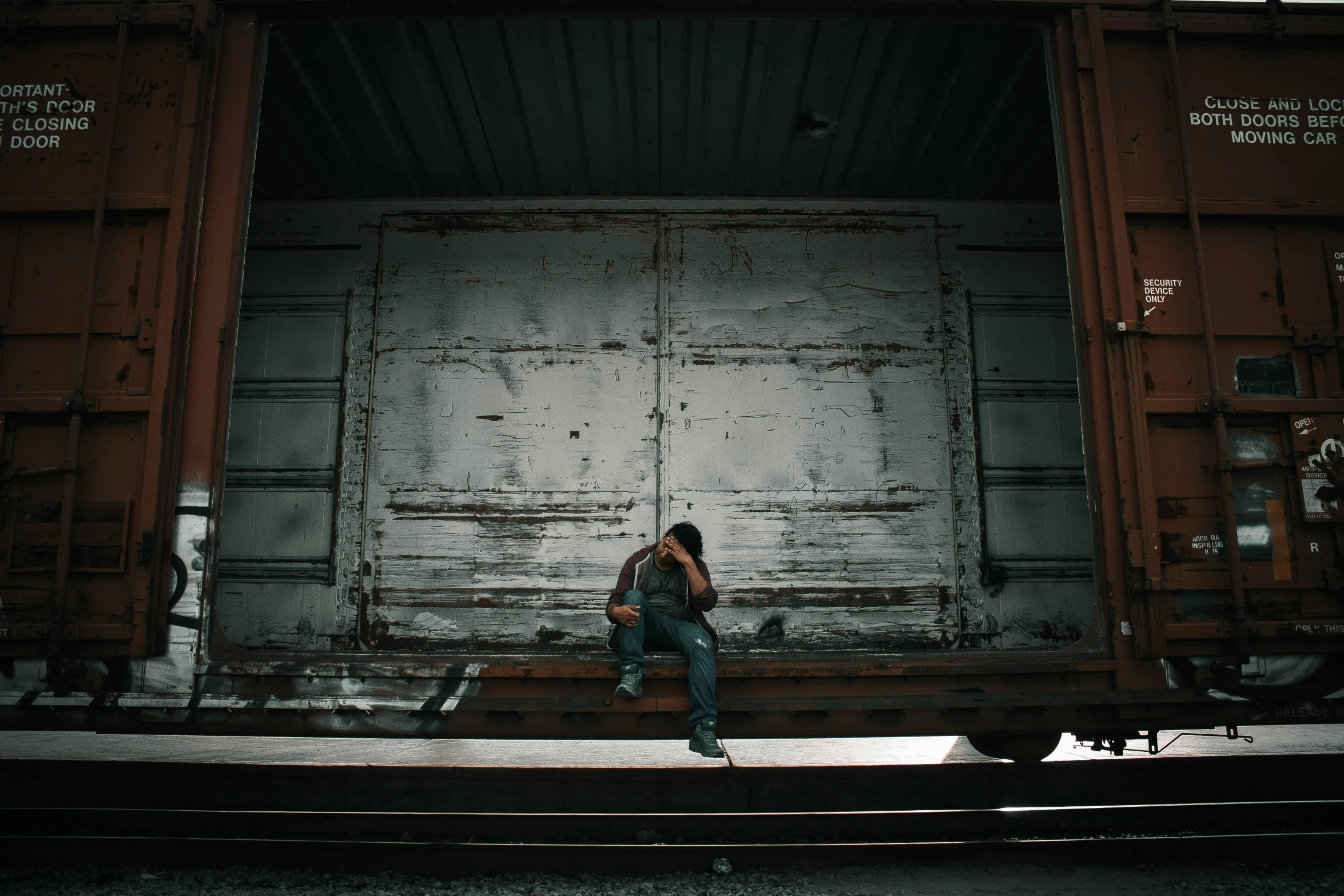 a man sitting on the side of a train track, pexels contest winner, graffiti, shipping containers, tears, ((rust)), low key