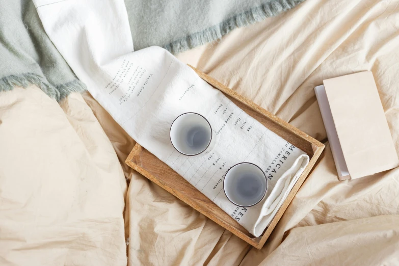 a tray with glasses sitting on top of a bed, inspired by Kanō Shōsenin, trending on unsplash, private press, soft grey and blue natural light, coffee stain on napkin, hidden message, high quality product photo