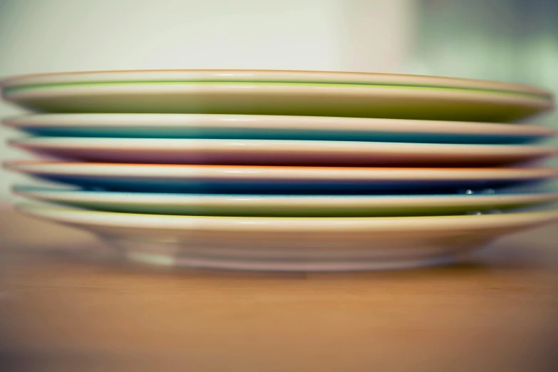 a stack of plates sitting on top of a wooden table, by Doug Ohlson, flickr, plasticien, modern pastel colours, entertaining, in a row, on a plate