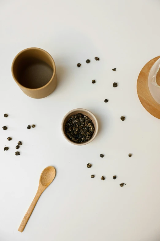 a white table topped with two cups of coffee and a wooden spoon, inspired by Cui Bai, minimalism, pepper, detailed product image, tea, beige mist