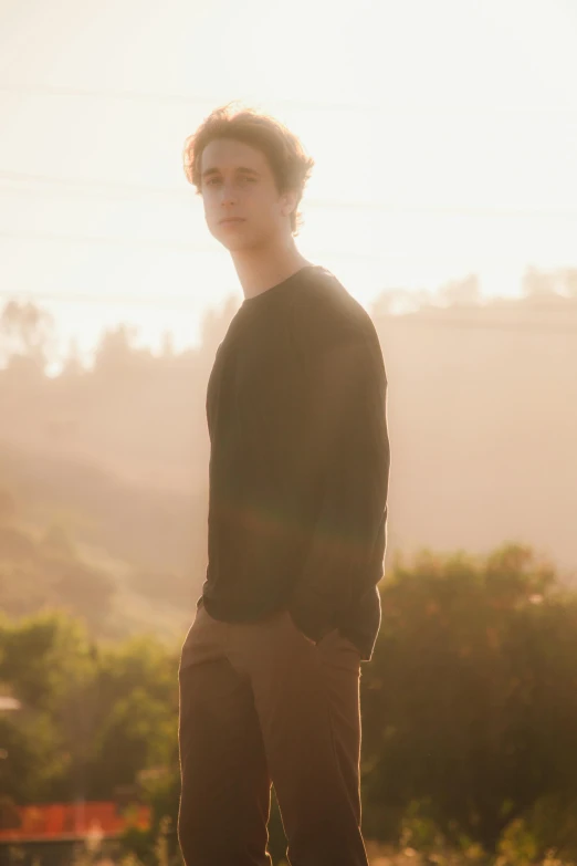 a young man standing on top of a skateboard, an album cover, unsplash, portrait of timothee chalamet, golden hour sunlight, a blond, standing on a cliffside