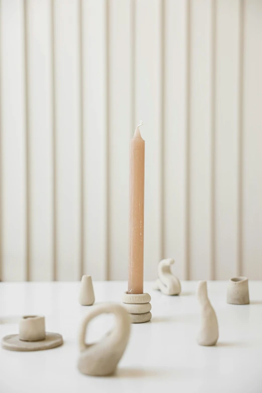 a candle sitting on top of a white table, an abstract sculpture, made out of clay, dwell, spire, inuk