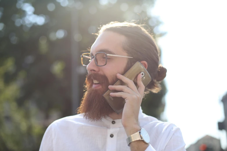 a man with a beard talking on a cell phone, by Niko Henrichon, happening, wearing square glasses, uploaded, brown, **cinematic