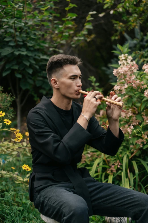 young man in black eating food out of the woods