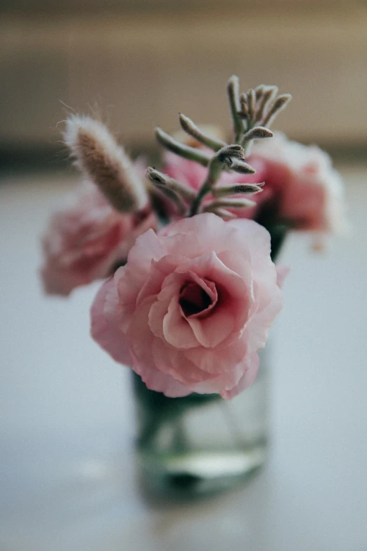 a small vase filled with pink flowers sitting on top of a table