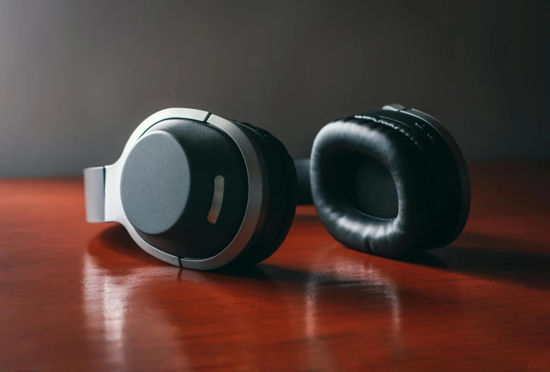 a pair of headphones sitting on top of a wooden table, pexels, bauhaus, black and silver, focus on two androids, comfortable, round ears