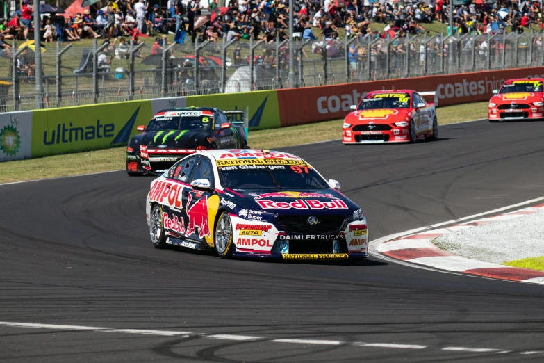 several cars racing on a race track near spectators