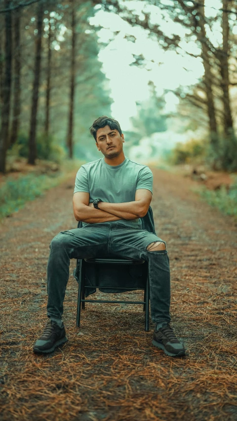 a man sitting on a chair in the middle of a forest, an album cover, by Ismail Acar, pexels contest winner, handsome young man, standing bravely on the road, jayison devadas, lgbtq