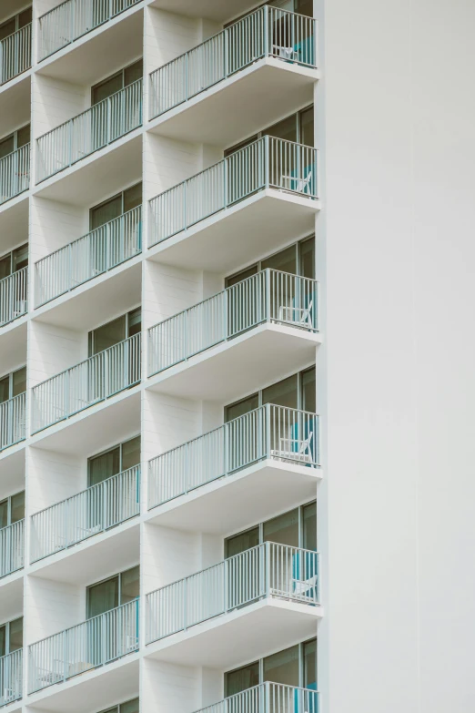 a tall white building with balconies and balconies, oceanside, balcony door, zoomed out view, exterior