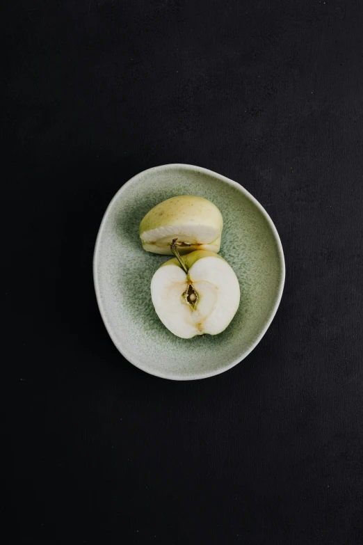 a green plate topped with sliced apples on top of a black table, inspired by Maruyama Ōkyo, unsplash, minimalism, organic ceramic white, petite pear slim figure, seeds, soft oval face