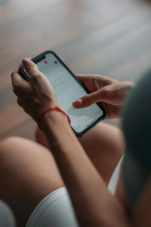 a woman sitting on the floor using a cell phone, trending on pexels, female calendar, sitting on a red button, dark. no text, ios