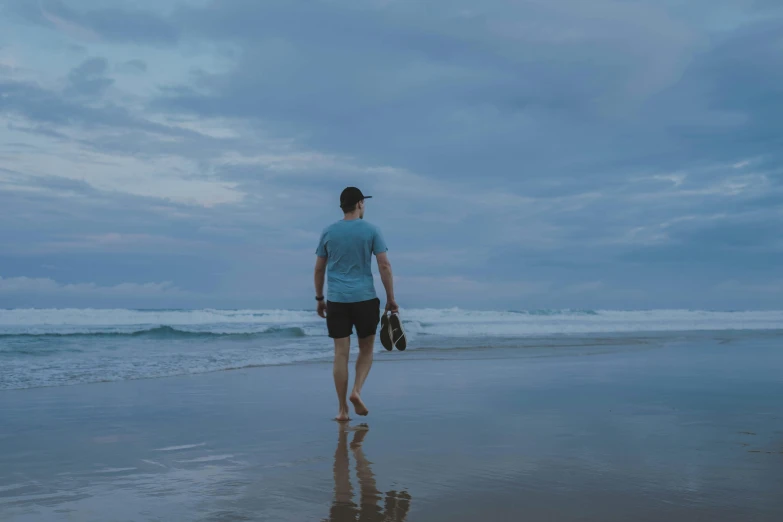 a person walking on the sand with a mitt in his hand