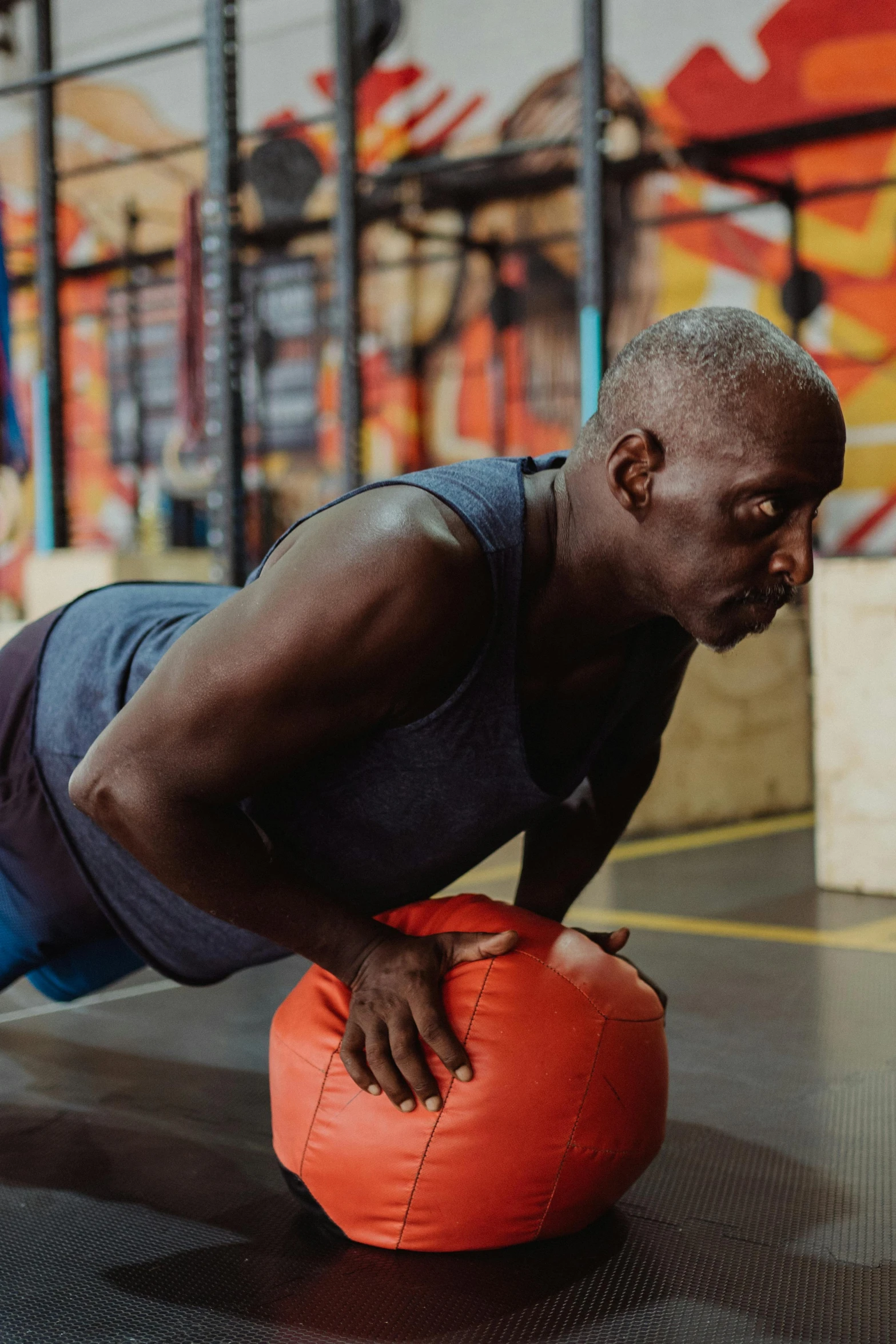 a man doing push ups on an orange ball, a portrait, pexels contest winner, older male, man is with black skin, lachlan bailey, in a gym