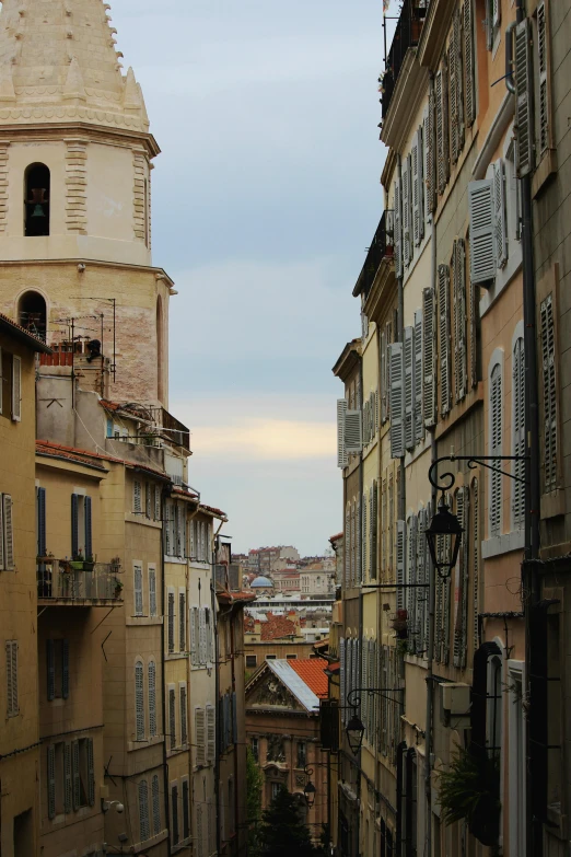 a narrow street with a clock tower in the background, inspired by Pierre Brissaud, renaissance, nice view, top of the hill, grey, domes