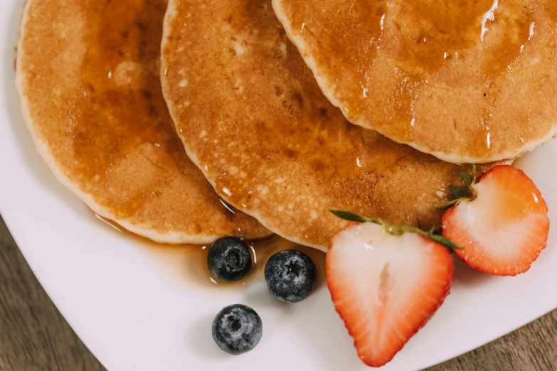 pancakes topped with syrup and blueberries on a plate