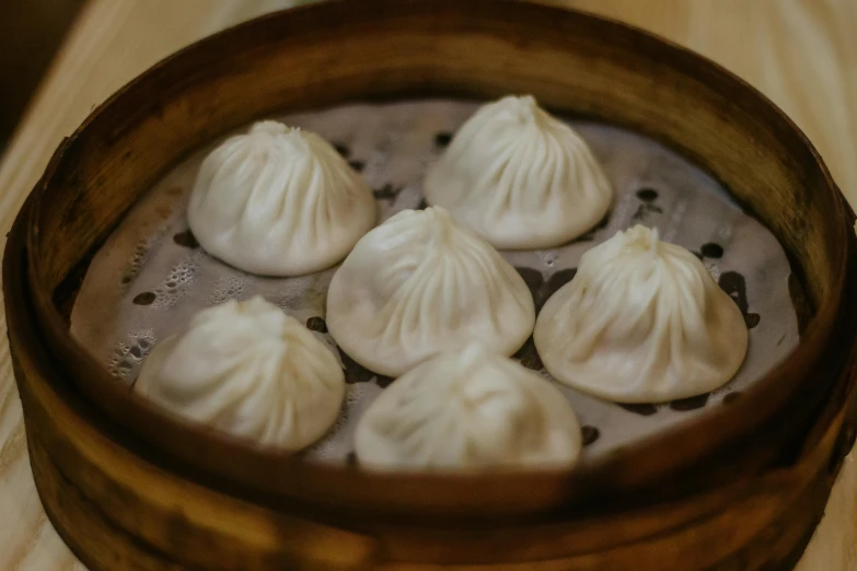 a wooden bowl filled with dumplings on top of a table, whitehorns, domes, highly upvoted, simon lee