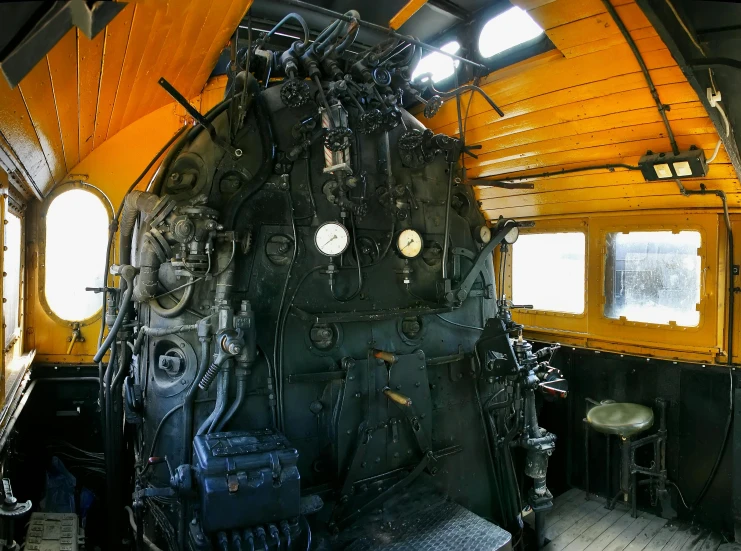 a train engine sitting inside of a train car, cockpit, yellow, manufactured in the 1920s, unimaginably huge