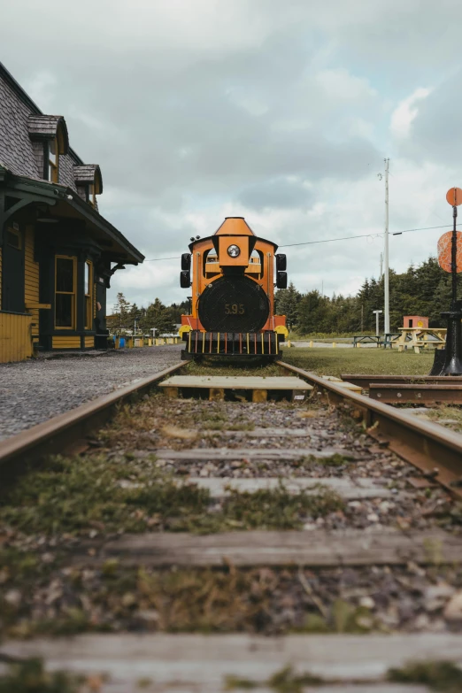 a train traveling down train tracks next to a train station, a portrait, by Jessie Algie, unsplash contest winner, quebec, preserved historical, engine, wooden platforms