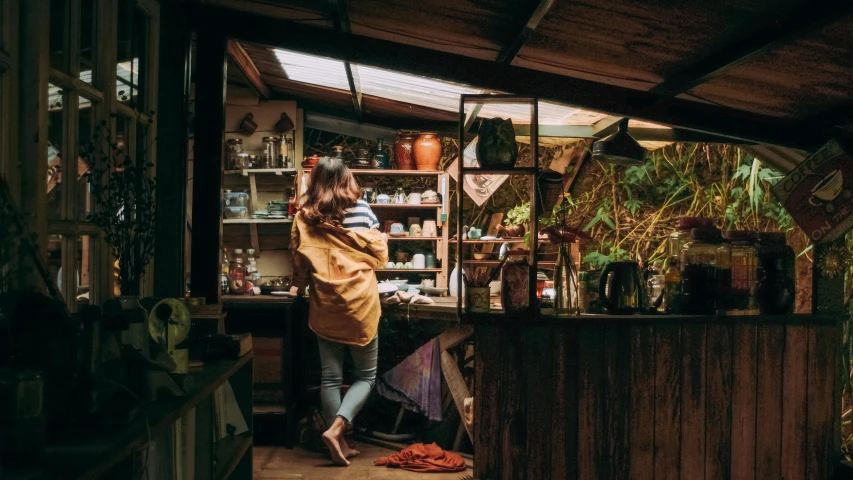 a woman standing in a kitchen next to a counter, inspired by Elsa Bleda, pexels contest winner, inside a shed, lush nature, busy night, permaculture