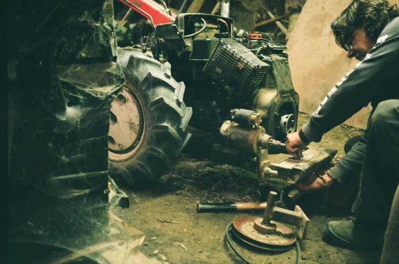 a man working on a tractor in a garage, an album cover, inspired by Elsa Bleda, pexels contest winner, auto-destructive art, wrecked technology, analogue, heavy-duty boots, portable generator