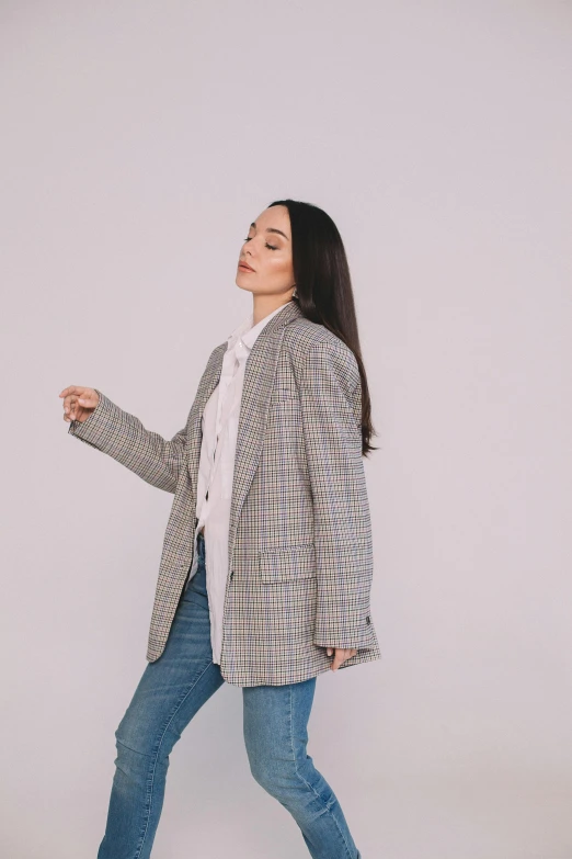 a woman in blue jeans and a black and white jacket walking