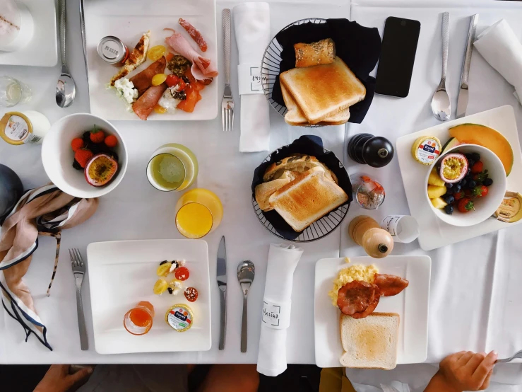 plates and bowls of food on white table cloth