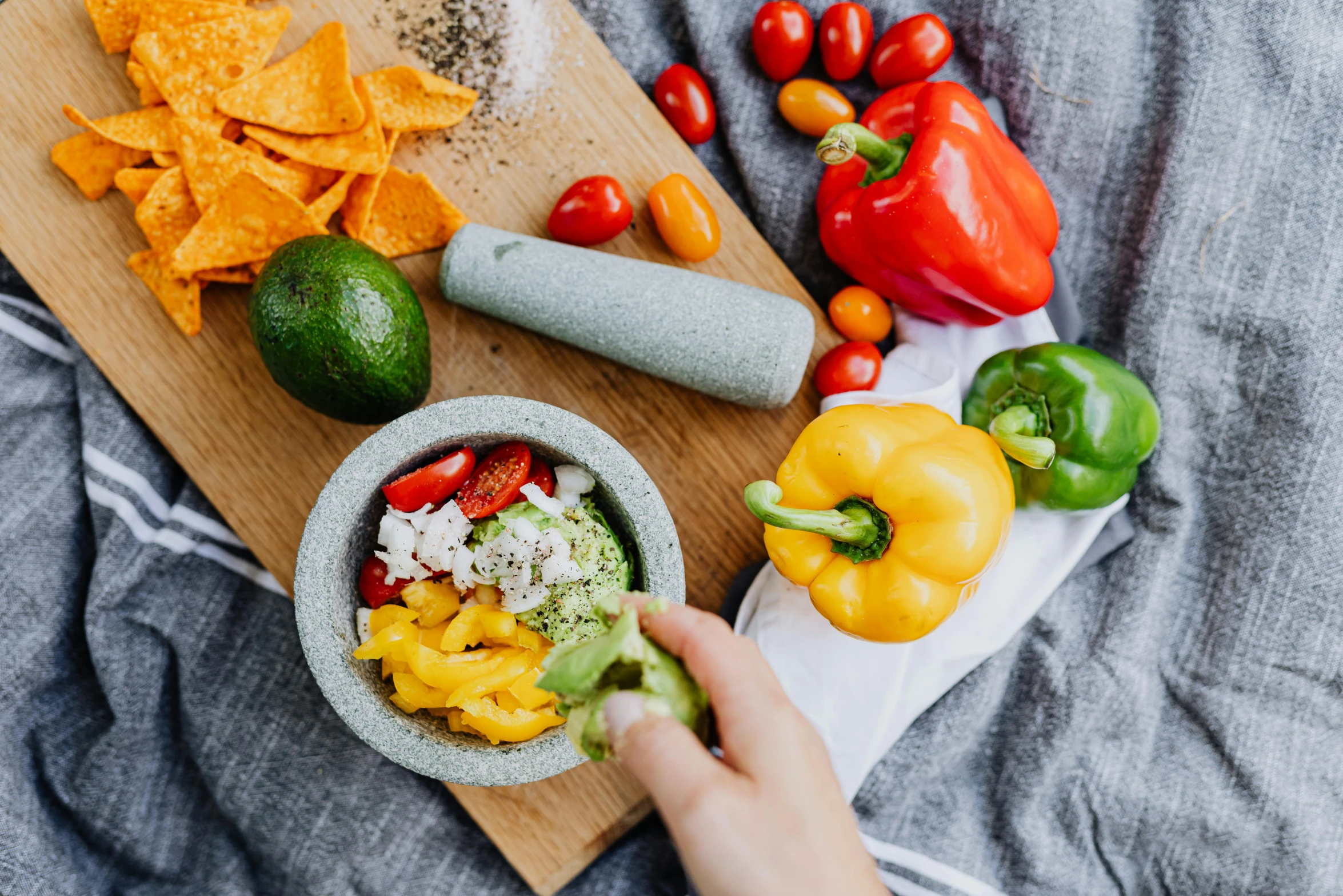 a person holding a bowl of food on top of a wooden cutting board, by Julia Pishtar, pexels contest winner, salsa tricks, 🦩🪐🐞👩🏻🦳, multicoloured, avocado and cheddar