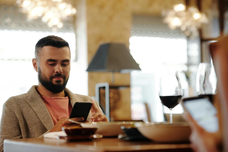 a man sitting at a table looking at his cell phone, pexels, figuration libre, avatar image, restaurant, lgbtq, ahmad merheb