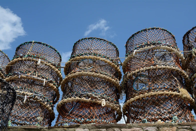 a pile of lobster cages sitting on top of a stone wall, by Alison Watt, pexels, circular towers, avatar image, sky blue, fishnets