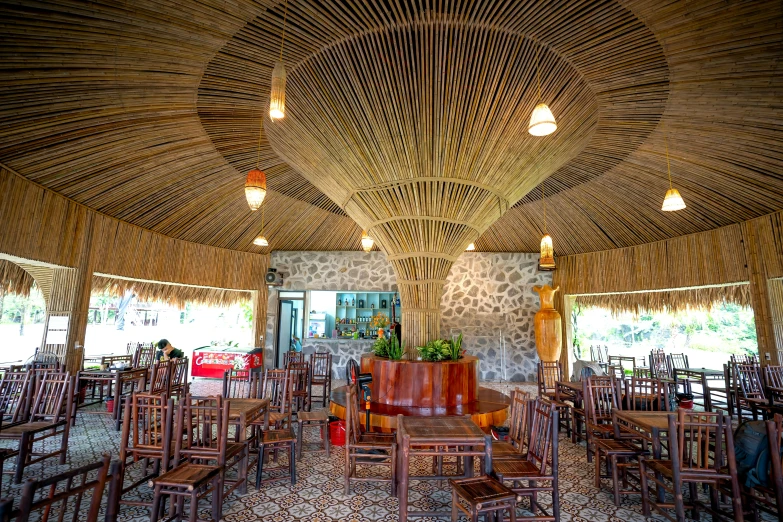 a large bamboo covered dining area with wooden chairs and tables