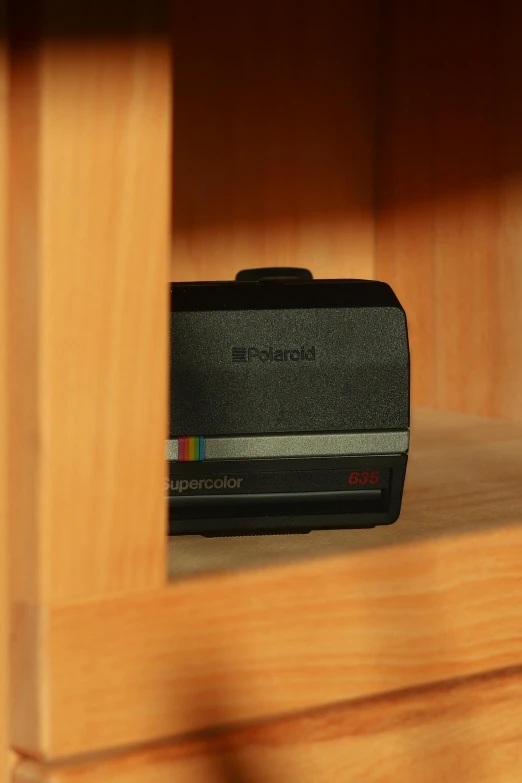 a polaroid camera sitting on top of a wooden shelf, a hologram, inspired by Richard Anuszkiewicz, happening, dusty library, arcade cabinet, close-up shot taken from behind, product shot