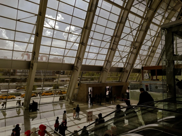 an airport with many people walking around and escalator