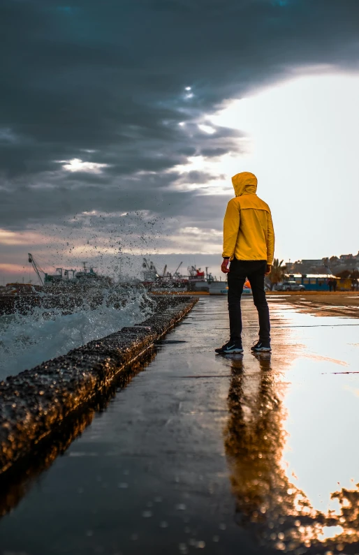 a person walking on wet pavement next to an ocean