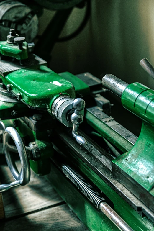 a green machine sitting on top of a wooden table, an engraving, pexels contest winner, lathe, steel plating, levers, iconic scene