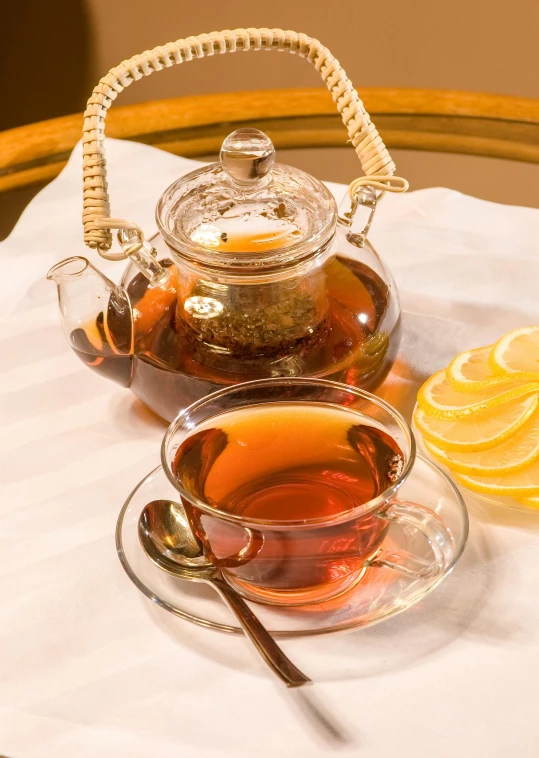 a tea pot sitting on top of a table next to a cup of tea, iced tea glass, thumbnail, honey, on display