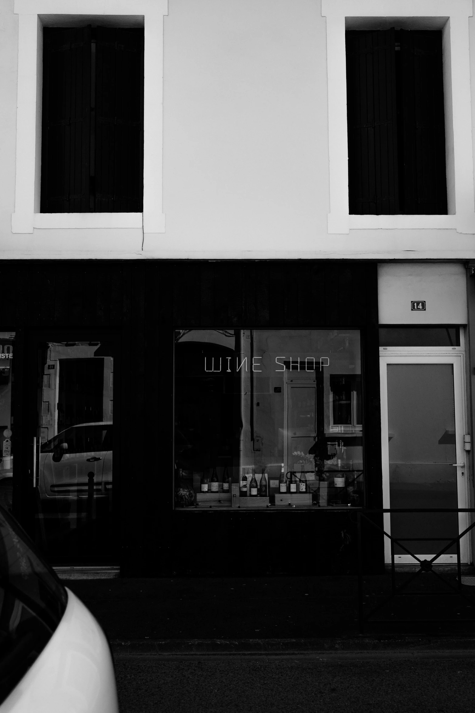 a white car parked in front of a building, a black and white photo, by Uwe Wittwer, purism, 12th century apothecary shop, style of denis villeneuve, with a whitish, black space