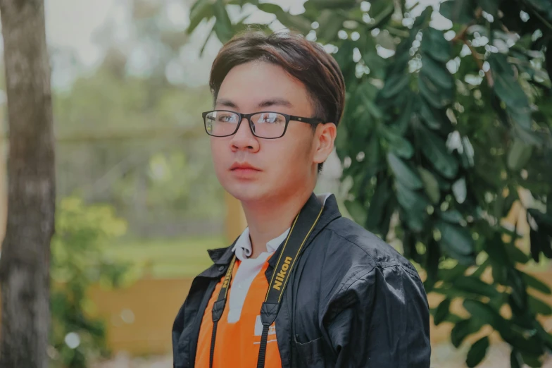 a man with glasses standing in front of a tree, a picture, inspired by Patrick Ching, pexels contest winner, photorealism, young cute wan asian face, orange hue, professional photo-n 3, student