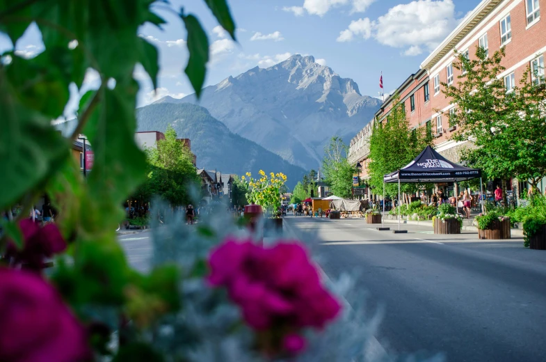 a city street with a mountain in the background, by Brigette Barrager, pexels contest winner, flowers around, canada, town square, clear and sunny